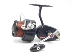 The Jack Hilton Mitchel 410 High Speed presentation fixed spool reel, dark blue gear housing and rotor, folding handle, bar anti-reverse lever, white script lettering, red Garcia transfer label, tungsten guide, circa 1966, with perspex stand and detail c