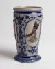 Westerwald stoneware cricket beaker, moulded in relief with three cameo panels of a batsman, after W.G. Grace, in different poses. The body highly decorated with vine and sprig decoration in cobalt blue on a grey background, with the figures highlighted i