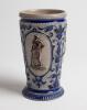 Westerwald stoneware cricket beaker, moulded in relief with three cameo panels of a batsman, after W.G. Grace, in different poses. The body highly decorated with vine and sprig decoration in cobalt blue on a grey background, with the figures highlighted i - 2