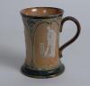 Doulton Lambeth stoneware mug decorated with three moulded relief vignettes of cricketers, a batsman, bowler and wicket keeper, Abel, Woods and McGregor in white on a brown background. With stylised floral leaf and flower Art Nouveau decoration to top and