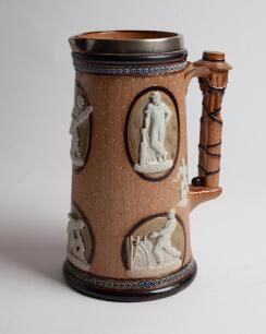 Cricketing jug. A large and impressive Doulton Lambeth stoneware tapering jug, moulded in relief with six raised figures, three of batsman, two of fielders and a wicket keeper in roundels, all different and in various positions. With two further smaller r