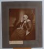 Albert Chevallier Tayler (1862-1925). Large sepia toned print, mounted to card, of a painting of Lord James of Hereford wearing robes sitting in a chair, presumably by Chevallier Tayler, the print with family crest to corner with the motto ‘Vim vi repelle