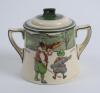 Royal Doulton &lsquo;Golfing series&rsquo; two handled sugar basin with lid, the body decorated with a continuous scene of cavalier figures (Crombie) of golfers and caddie playing golf with proverb inscription &lsquo;Promise little and do much&rsquo;, decorated with green line d