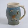 Royal Doulton Queensware blue mug/tankard with a golf scene of cavalier golfer with caddie (Charles Crombie) to one side and a smaller group playing golf to verso. Royal Doulton mark to the bottom of the mug. 5.5” tall. Circa 1930. Very good condition