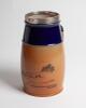 Royal Doulton golf jug in brown with cobalt blue collar and silver rim, decorated with a golfing (cavalier) scene, with motto, &lsquo;A ball is lost if it be not found within five minutes&rsquo;. 8.75&rdquo; tall. Doulton mark to base, numbers 8820.BB5. Reg no 525512. Silv - 2
