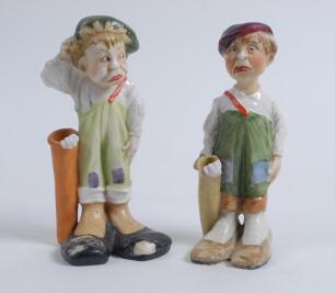 Comical Golf caddies. A pair of humorous golf caddies, each carrying a golf bag, both with enormous feet, both with glum faces. Made by Stellmacher Teplitz (Austria) Circa 1920/30’s?. Approximately 7.25” tall. Marks to base. Minor wear otherwise in good c