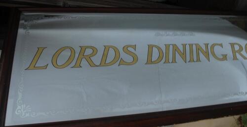 ‘Lords Dining Room’. Very large and heavy mirror with title to centre extending almost the full width of the glass. The construction appears to comprise an outer layer of bevel-edged glass with lettering painted to the reverse in gold with black outline, 