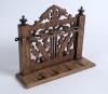 Wooden pipe rack. Nice pipe rack with slots for four pipes and intricate fret work, the design featuring two cricket bats and balls with turned finials. Hand written date &lsquo;1914&rsquo; to base. Small loss to one finial, otherwise in good condition