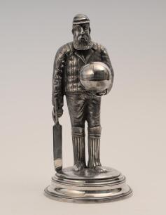 William Gilbert Grace. Gloucestershire & England. Large and impressive silver plated full length figure of Grace wearing cap and pads and carrying a bat to right hand, his left hand is holding a very large cricket ball with a circular hole to the top whic