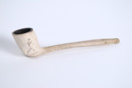 Cricket pipe. Early clay pipe with batsman stood at the wicket to one side and to the other aset of three stumps with a bat leaning against them. The pipe was made by William Luckett of Plumstead. With &lsquo;Luckett&rsquo; and &lsquo;Plumstead&rsquo; impressed to the stem of th