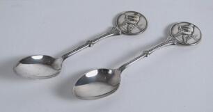 Cricket spoons. A pair of silver plated spoons each with a similar figure of a batsman at the wicket to top of handle. Sold with a small ceramic cricket cup with image of a batsman and a golfing saucer, cracks to the saucer. G