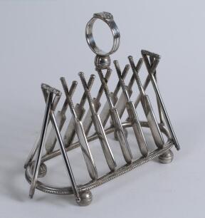 Cricket toast rack c1900. A Victorian silver plated, six division toast rack with five pairs of crossed cricket bats, with a set of angled cricket stumps and bails at each end, the handle of the rack in the form of a cricketer&rsquo;s belt and buckle on a crick