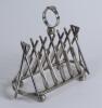 Cricket toast rack c1900. A Victorian silver plated, six division toast rack with five pairs of crossed cricket bats, with a set of angled cricket stumps and bails at each end, the handle of the rack in the form of a cricketer&rsquo;s belt and buckle on a crick