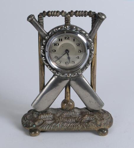 Cricket clock. A Victorian brass mantel clock. The case in the form of a set of stumps with silver base metal crossed bats and ball on an oval naturalistic case base with bun feet. Professionally restored modern workings and dial. Approximately 6.5&rdquo; high 