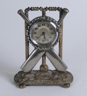 Cricket clock. A Victorian brass mantel clock. The case in the form of a set of stumps with silver base metal crossed bats and ball on an oval naturalistic case base with bun feet. Professionally restored modern workings and dial. Approximately 6.5&rdquo; high 