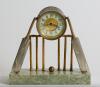 Cricket clock. A Victorian brass mantel clock. An attractive late Victorian/ Edwardian brass clock of cricketing interest, formed with a central drum form enamelled dial and workings attached two sets of cricket stumps and bails with cricket bats leaning 