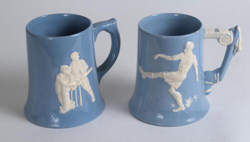 Dartmouth Pottery. Two blue and white tankards, one of cricket with a batsman and wicket -keeper to one side and bowler to the other and the other, football with player kicking the ball to one side and ball and part of the goal to the other. The football 