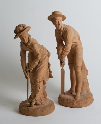 &lsquo;Cricket & Croquet&rsquo;. A unusual pair of nineteenth century unglazed terracotta earthenware figures. One of a boy batsmen, wearing broad banded boater, wearing pads and with bat and stance ready to receive the ball and the other of a young woman wearing dre