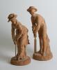 &lsquo;Cricket & Croquet&rsquo;. A unusual pair of nineteenth century unglazed terracotta earthenware figures. One of a boy batsmen, wearing broad banded boater, wearing pads and with bat and stance ready to receive the ball and the other of a young woman wearing dre