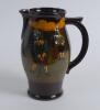 A large Royal Doulton Kingsware pitcher with a golf scene of cavalier golfer with caddie (Charles Crombie) to one side and a smaller group playing golf to verso. Royal Doulton mark to the bottom of the jug. 9&rdquo; tall. Circa 1930. Very good condition