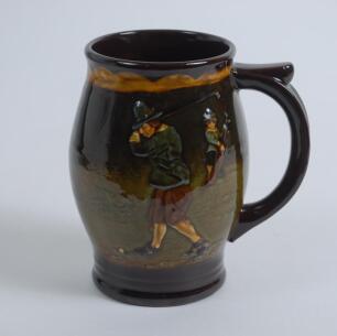 Royal Doulton Kingsware brown mug/tankard with a golf scene of cavalier golfer with caddie (Charles Crombie) to one side and a smaller group playing golf to verso. Royal Doulton mark to the bottom of the mug. 5.5&rdquo; tall. Circa 1930. Very good condition