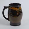 Royal Doulton Kingsware brown mug/tankard with a golf scene of cavalier golfer with caddie (Charles Crombie) to one side and a smaller group playing golf to verso. Royal Doulton mark to the bottom of the mug. 5.5&rdquo; tall. Circa 1930. Very good condition - 2