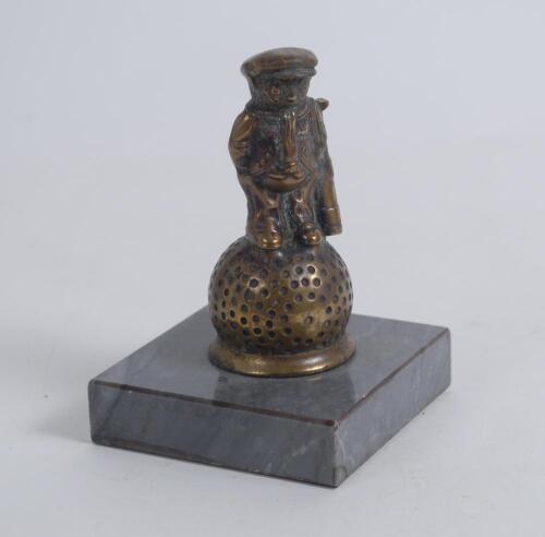 &lsquo;Golf counter bell. A cast brass counter bell in the form of a comical figure of a golf caddie with a golf ball for his head, standing on a larger golf ball. It dates to approximately the 1940/50s and was designed by the popular artist John Hassall in the