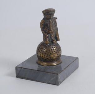 &lsquo;Golf counter bell. A cast brass counter bell in the form of a comical figure of a golf caddie with a golf ball for his head, standing on a larger golf ball. It dates to approximately the 1940/50s and was designed by the popular artist John Hassall in the