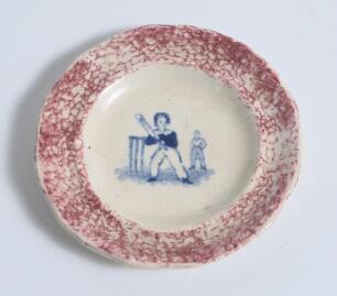 Child&rsquo;s plate/dish. Very small early Victorian Staffordshire child&rsquo;s plate with centre image vignette of a boy batsman holding a bat in the air in front of the wicket with fielder behind in blue, speckled pink outer border. 3.5&rdquo; diameter. Circa 1860. Circ
