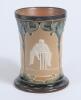 Doulton Lambeth stoneware waisted ceramic tankard with three moulded relief vignettes of cricketers, a batsman, bowler and wicket keeper in white on brown background. With stylised floral leaf and flower decoration to top and beneath in green and light bl - 2