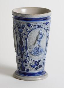 Westerwald stoneware cricket beaker, moulded in relief with three cameo panels of a batsman, after W.G. Grace, in different poses. The body highly decorated with vine and sprig decoration in cobalt blue on a grey background, with the figures highlighted i