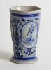 Westerwald stoneware cricket beaker, moulded in relief with three cameo panels of a batsman, after W.G. Grace, in different poses. The body highly decorated with vine and sprig decoration in cobalt blue on a grey background, with the figures highlighted i