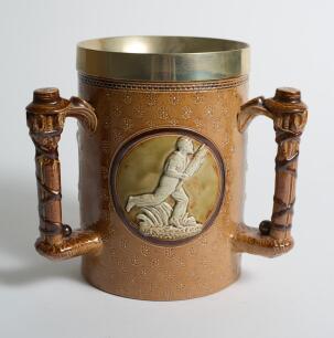 Doulton Lambeth stoneware tyg. Large and impressive three handled tyg with three moulded relief vignettes of cricketers, a batsman, a fielder and wicket keeper in white on a green cameo background, the sides highly decorated in a small floral pattern in b