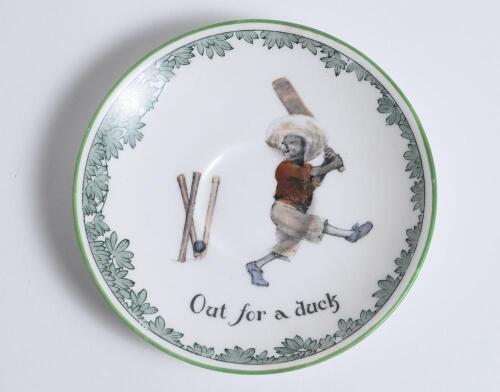 &lsquo;Out for a Duck&rsquo; Royal Doulton Black Boy saucer, entitled &lsquo;Out for a Duck&rsquo; printed with a boy in red shirt and a floppy hat in batting pose having attempted a big shot, looking back to see the ball hit his wicket. Green floral decoration to edge. 5.5&rdquo; dia