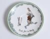 &lsquo;Out for a Duck&rsquo; Royal Doulton Black Boy saucer, entitled &lsquo;Out for a Duck&rsquo; printed with a boy in red shirt and a floppy hat in batting pose having attempted a big shot, looking back to see the ball hit his wicket. Green floral decoration to edge. 5.5&rdquo; dia