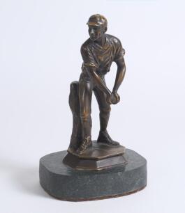Cricket fielder. Bronze type metal featuring a fielder picking up the ball and holding it with both hands about to throw in. The fielder is wearing a cap and the figure is mounted to a marble stone oval plinth. 10&rdquo; tall. Very good condition