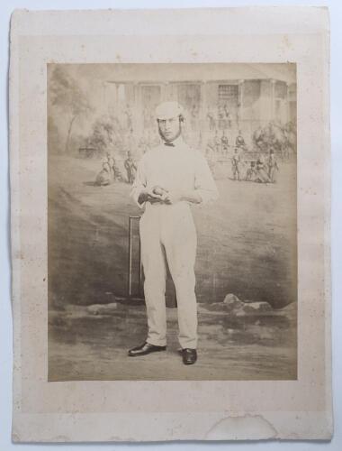 Edward Mills Grace. Gloucestershire, M.C.C. & England 1870-1896. Early large original sepia studio posed photograph of Grace in full cricket attire and wearing a cap, aged 21. The photograph, taken in 1862, shows Grace standing in front of a wicket holdin
