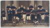 Rugby Union. Wakefield Trinity Rugby Football Club c.1879. Large and early original mono photograph heightened in club colours of red and blue of the Wakefield Trinity team with the Yorkshire Challenge Cup trophy, standing on the stone steps of what appea