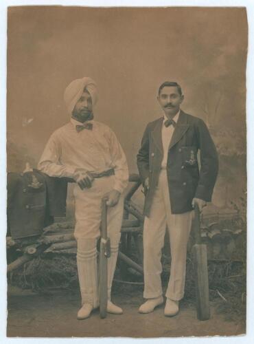 Kumar Shri Ranjitsinhji. Cambridge University, Sussex, London County & England 1893-1920. Original sepia studio portrait photograph of Ranji standing full length alongside another Indian cricketer in a turban. Both players wearing cricket attire and bow t