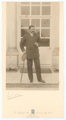 Kumar Shri Ranjitsinhji. Cambridge University, Sussex, London County & England 1893-1920. Excellent original sepia photograph of Ranjitsinhji, wearing suit and tie, with a cigarette in his left hand and leaning on a walking stick with cap to hand, The pho