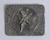 &lsquo;Run&rsquo;. Early Victorian embossed oblong brass belt buckle, with clasp and flat hook to back, depicting to centre a batsman running between the wickets and losing his boater/hat, fielder, the other batsman and ball to background. To all four corners of buck