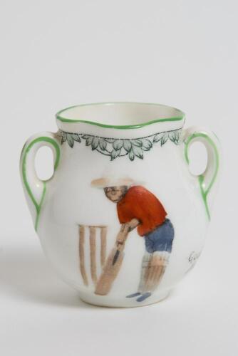 &lsquo;Good for Fifty&rsquo;. Royal Doulton Black Boy miniature two handled vase, with printed image of a boy in red shirt and a floppy hat in batting pose in front of the wicket to one side and to the other, a crest with &lsquo;The All Black Team&rsquo;. Green floral decoration