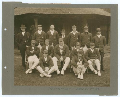 Australia tour to England 1921. Excellent original sepia photograph of fourteen playing members of the Australian touring party seated and standing in rows in front of a thatched pavilion, eleven wearing cricket attire, tour blazers and caps, the others i