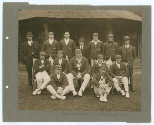 Australia tour to England 1921. Excellent original sepia photograph of fourteen playing members of the Australian touring party seated and standing in rows in front of a thatched pavilion, eleven wearing cricket attire, tour blazers and caps, the others i