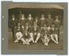 Australia tour to England 1921. Excellent original sepia photograph of fourteen playing members of the Australian touring party seated and standing in rows in front of a thatched pavilion, eleven wearing cricket attire, tour blazers and caps, the others i