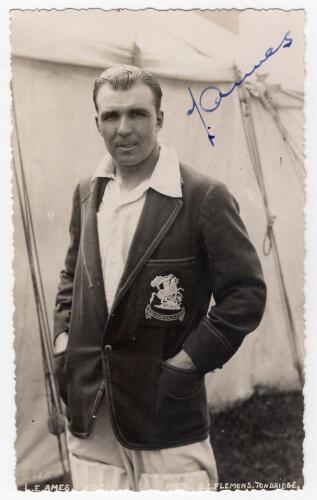 Leslie Ethelbert George &lsquo;Les&rsquo; Ames. Kent & England 1926-1951. Mono real photograph postcard of Ames standing three quarter length behind a marquee, wearing an M.C.C. blazer for the 1932/33 &lsquo;Bodyline&rsquo; tour to Australia. Nicely signed in blue ink to the pho