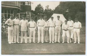 Lancashire at Bournemouth 1914. Early mono real photograph postcard of the Lancashire team standing in one row wearing cricket attire and caps, with the pavilion and spectators in the background for the match v Hampshire. Printed title to lower margin &lsquo;La
