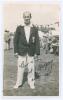 Robert James &lsquo;Bob&rsquo; Gregory. Surrey 1925-1947. Sepia real photograph postcard of Gregory standing full length wearing Surrey blazer, spectators and marquees in the background. Nicely signed in ink to the photograph by Gregory and dated 25th August 1934. Pu