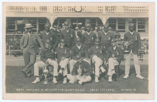 &lsquo;West Indians v. Uttoxeter OldFields (West Indians)&rsquo; 1906. Rare and early sepia real photograph postcard of the West Indies team seated and standing in rows wearing caps and blazers with three silver trophies, the pavilion in the background. The printed t