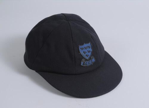 Allan Peter Wells. Sussex, Kent & England 1981-2000. Sussex navy blue cloth cap, with embroidered emblem of the six martlets and &lsquo;S.C.C.C.&rsquo; below worn by Wells during his career. Nickname &lsquo;Bomber&rsquo; to inside label. The cap was given by Wells to Ken Higgs o